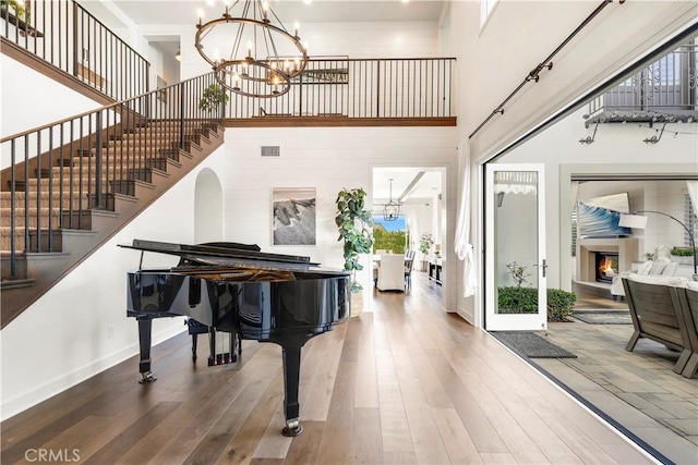 foyer entrance featuring a chandelier, visible vents, a lit fireplace, and wood finished floors