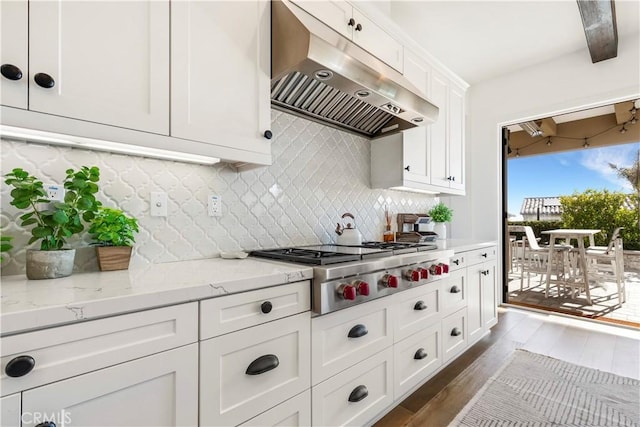 kitchen featuring backsplash, under cabinet range hood, stainless steel gas cooktop, dark wood finished floors, and white cabinetry