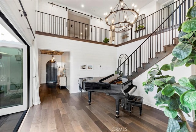 staircase with an inviting chandelier, a towering ceiling, and wood-type flooring