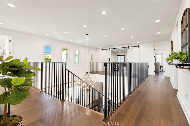 hall with a wealth of natural light, wood finished floors, and recessed lighting