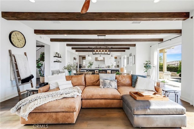 living room with baseboards, beam ceiling, and wood finished floors