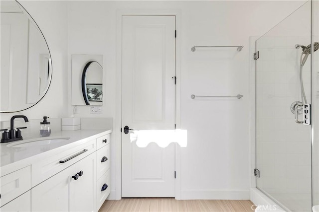 bathroom featuring wood finished floors, a stall shower, and vanity