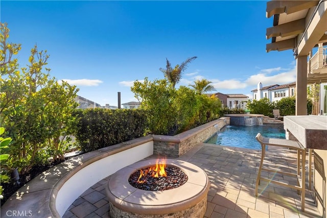 view of pool with a patio, an outdoor fire pit, and a pool with connected hot tub