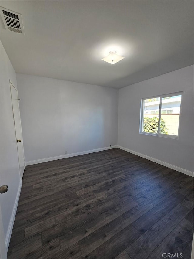 unfurnished room with dark wood finished floors, baseboards, and visible vents