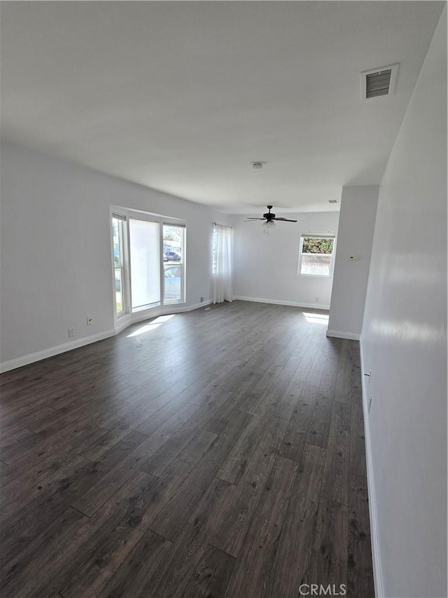 spare room with dark wood-type flooring, baseboards, visible vents, and ceiling fan