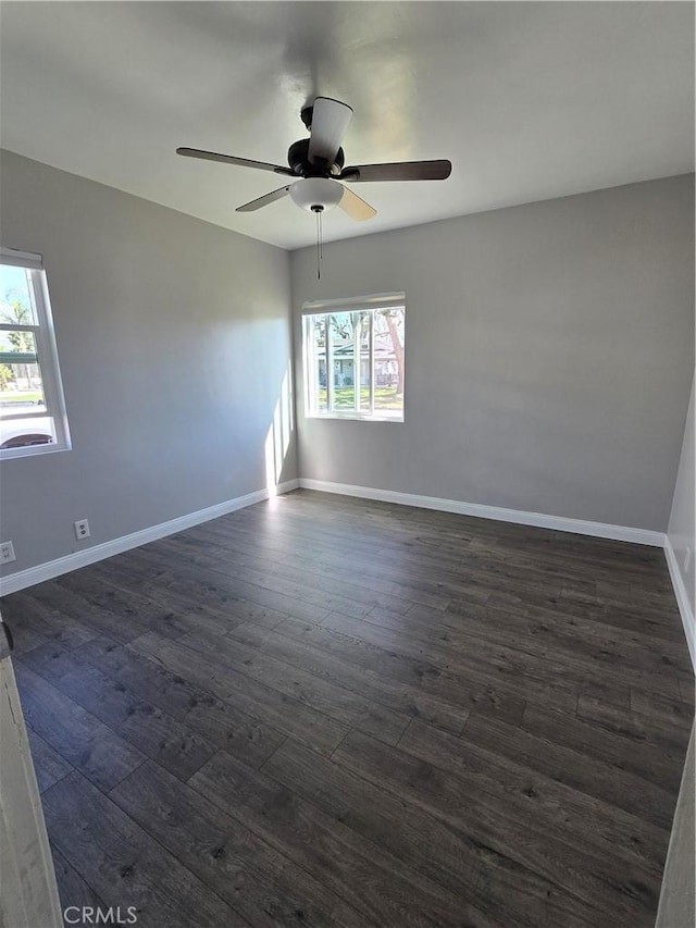 spare room with baseboards, dark wood-type flooring, and a ceiling fan