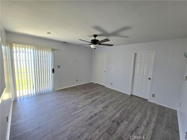 empty room with dark wood-style floors, baseboards, and ceiling fan