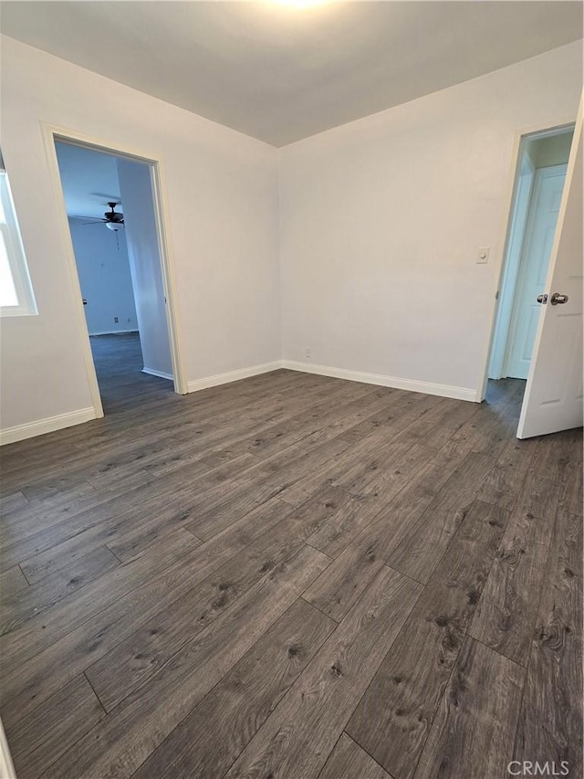 spare room featuring baseboards, dark wood-style flooring, and ceiling fan