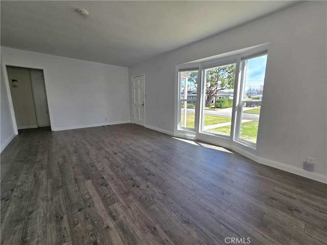 spare room with baseboards and dark wood finished floors