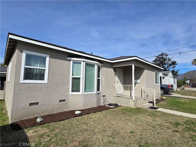 view of front of property with a front lawn, stucco siding, and crawl space