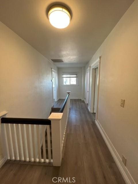 hall featuring an upstairs landing, dark wood-style flooring, and baseboards