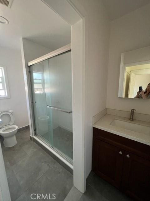 bathroom featuring a shower stall, toilet, and vanity