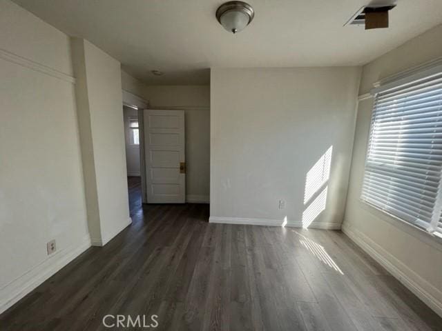 unfurnished room with visible vents, wood finished floors, and baseboards