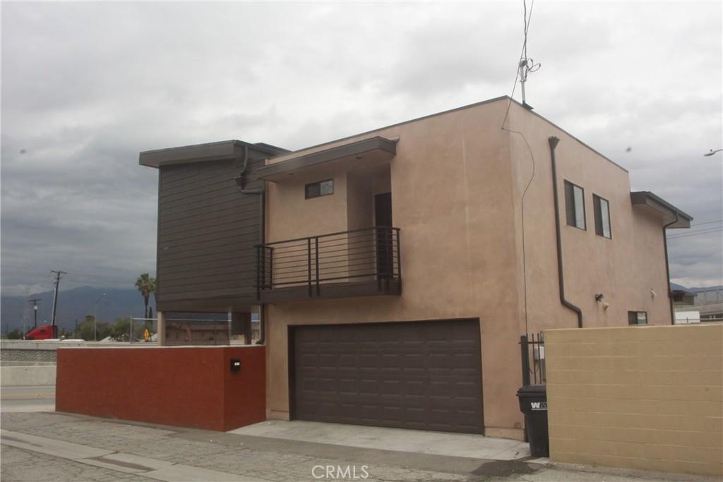 view of front facade with stucco siding, an attached garage, and a balcony