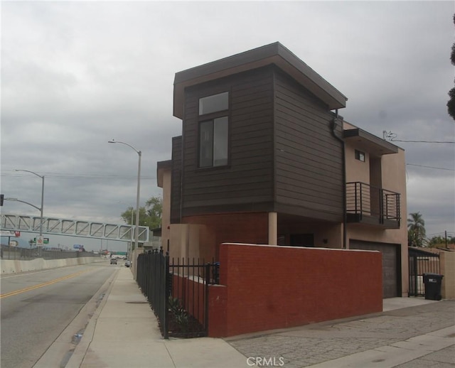 view of side of home featuring stucco siding, a garage, a fenced front yard, and a gate