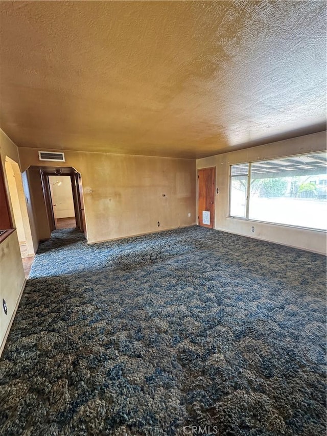 unfurnished room with visible vents, carpet, and a textured ceiling