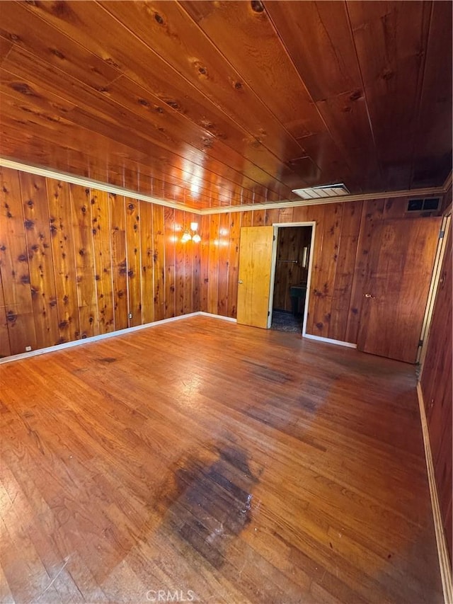 unfurnished living room with visible vents, wood walls, wood ceiling, and hardwood / wood-style flooring