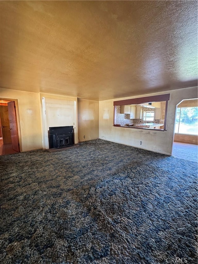 unfurnished living room featuring a textured ceiling and carpet flooring