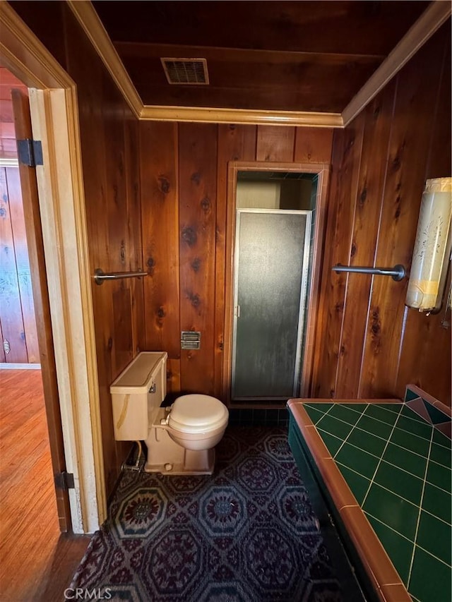 bathroom with tile patterned floors, visible vents, a shower stall, and wooden walls