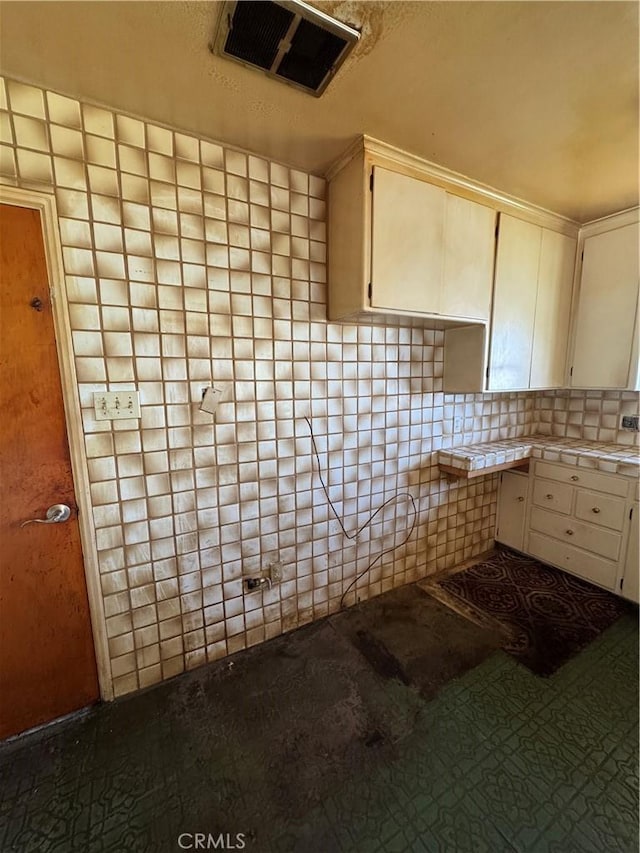 kitchen with visible vents, white cabinetry, and tile counters