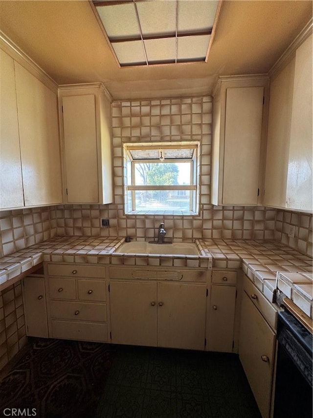 kitchen with backsplash, white cabinets, tile countertops, and a sink