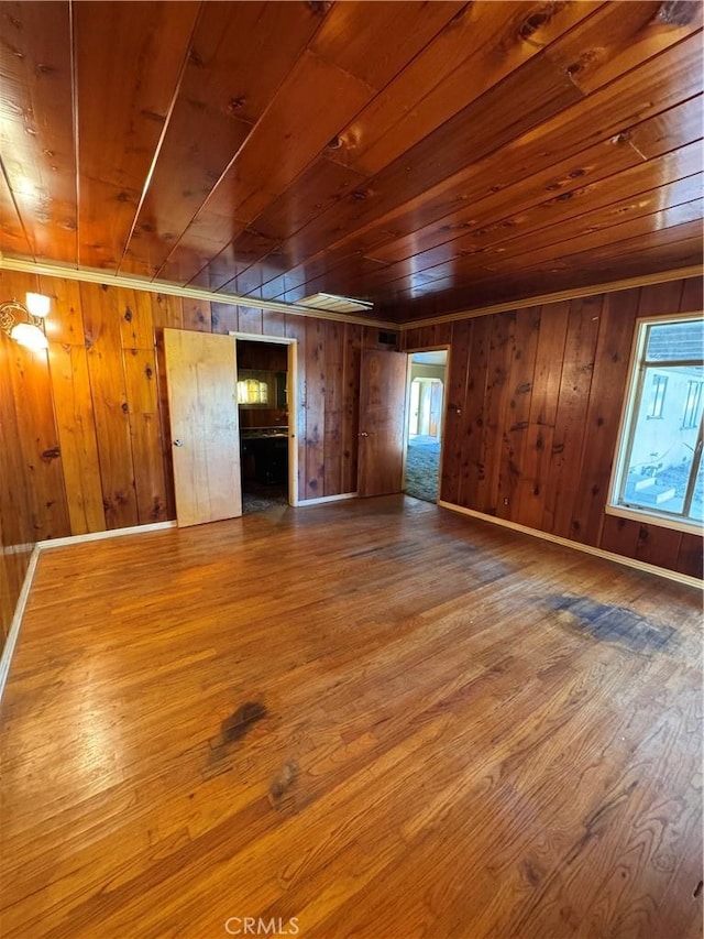 unfurnished living room featuring wood walls, wood ceiling, baseboards, and wood finished floors