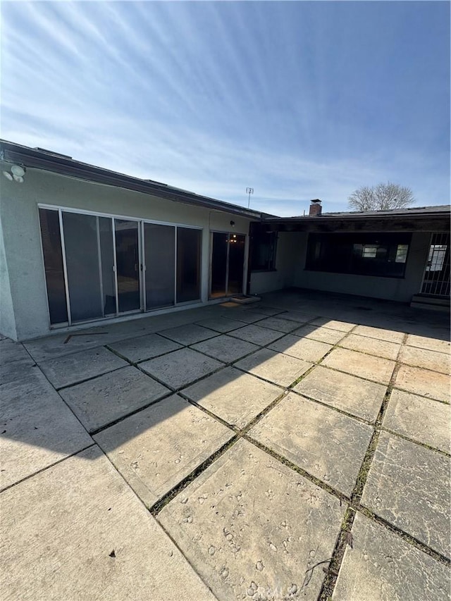 rear view of house featuring a patio and stucco siding