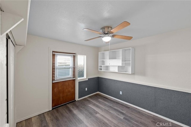 spare room with baseboards, dark wood-type flooring, ceiling fan, and a textured ceiling