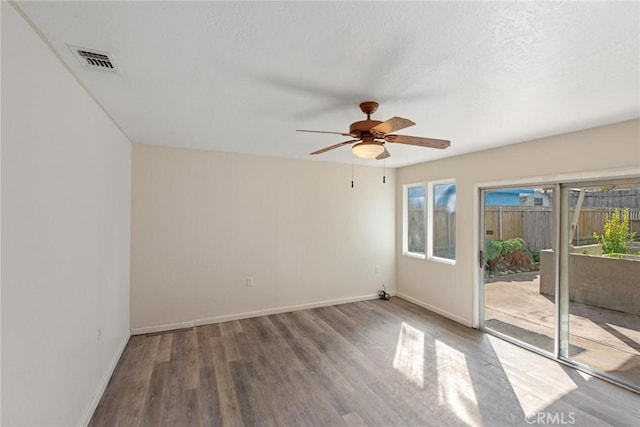 empty room featuring visible vents, a textured ceiling, wood finished floors, baseboards, and ceiling fan