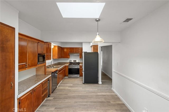 kitchen with a skylight, light wood-style flooring, appliances with stainless steel finishes, and a sink