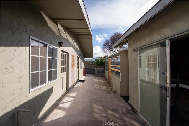 view of side of property featuring a patio area, stucco siding, and fence