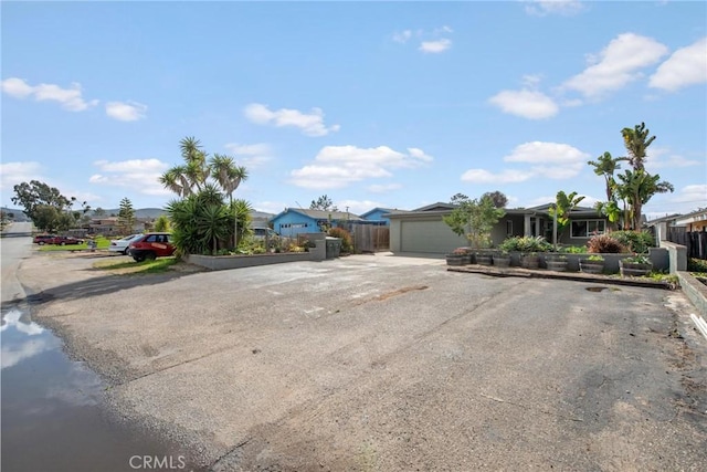 view of front facade featuring a residential view, fence, a garage, and driveway