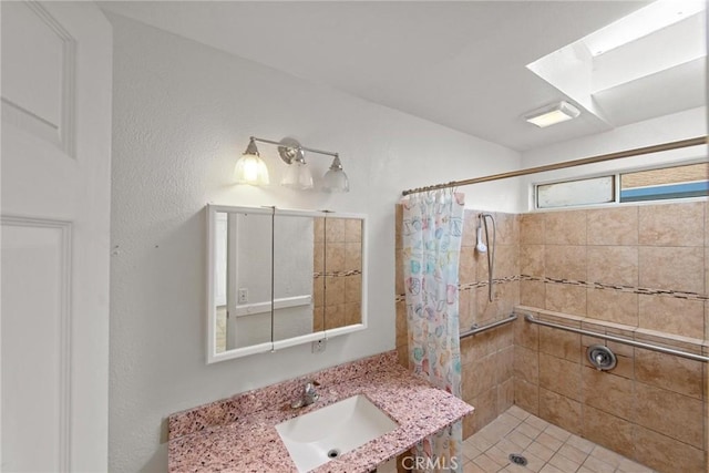 bathroom with vanity, a skylight, and tiled shower