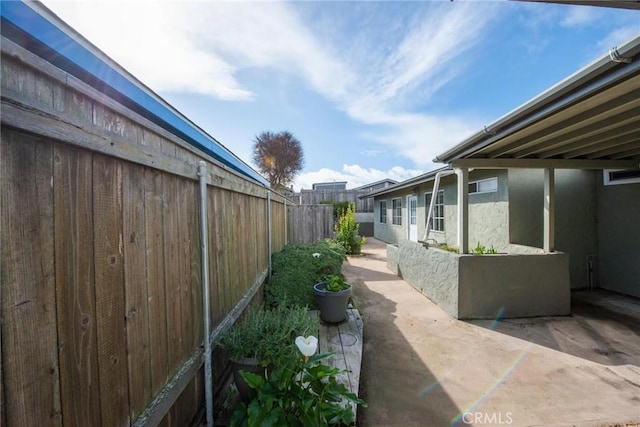 view of home's exterior with stucco siding, fence, and a patio area