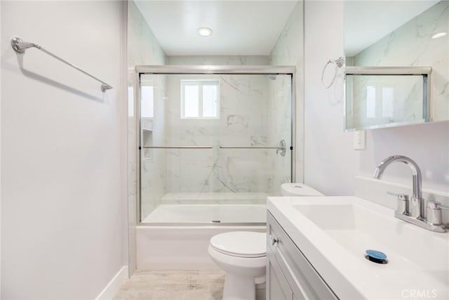 bathroom with vanity, toilet, and combined bath / shower with glass door