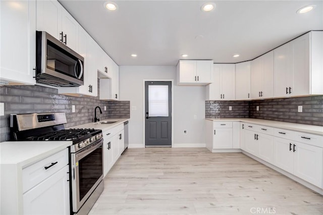 kitchen featuring light countertops, recessed lighting, light wood-style flooring, appliances with stainless steel finishes, and a sink