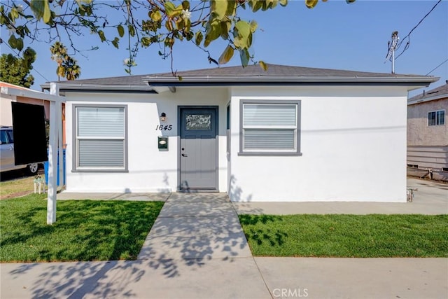 view of front of property with stucco siding and a front lawn