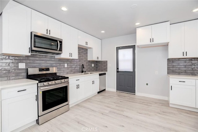 kitchen featuring a sink, light wood-style floors, appliances with stainless steel finishes, white cabinets, and light countertops