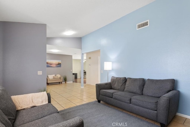 living area with tile patterned floors, visible vents, lofted ceiling, and baseboards