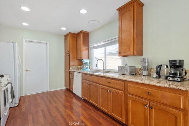 kitchen featuring white appliances, light stone counters, recessed lighting, dark wood-style flooring, and a sink