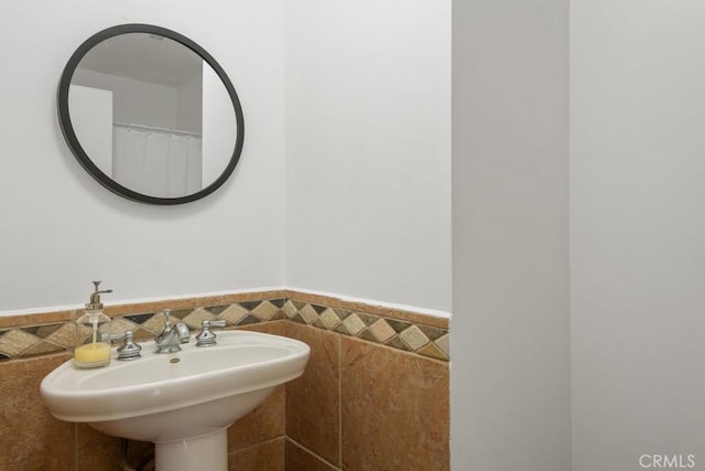 bathroom featuring wainscoting, tile walls, and a sink