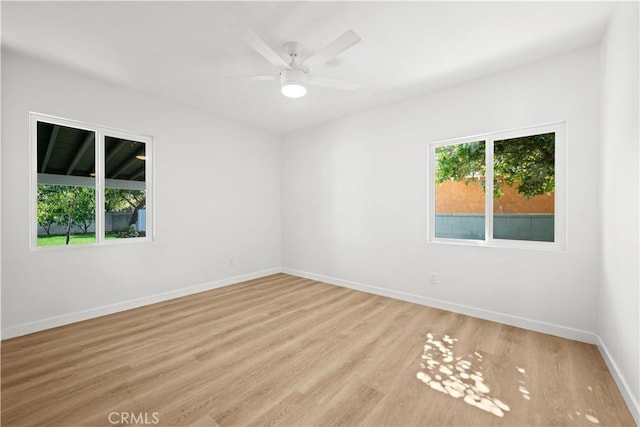 empty room featuring a ceiling fan, baseboards, and light wood finished floors