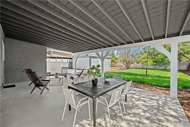 view of patio featuring outdoor dining space, an outbuilding, and a fenced backyard