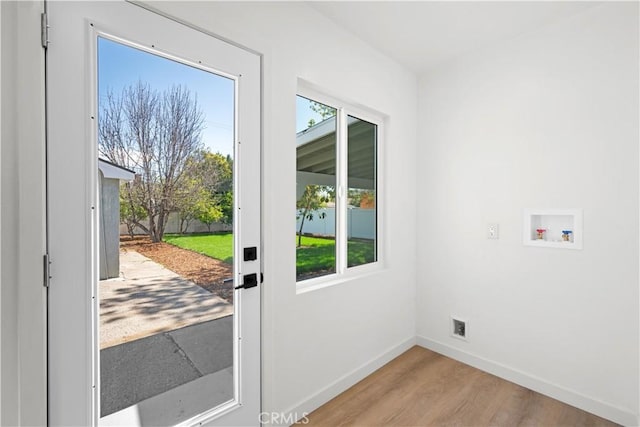 doorway to outside featuring baseboards and light wood-style floors