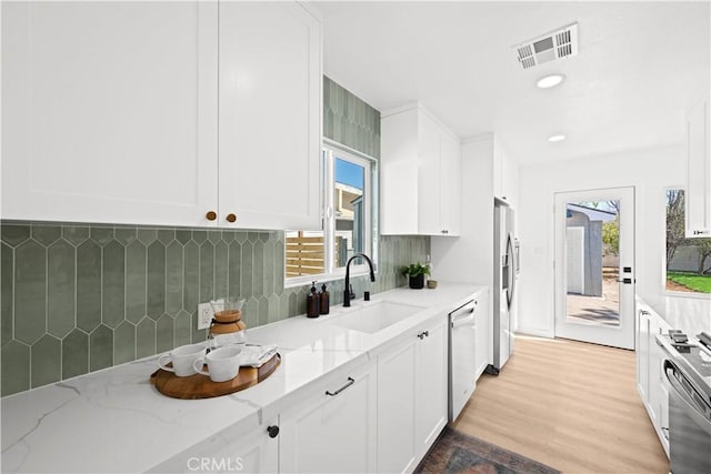 kitchen with visible vents, a sink, white cabinets, range, and dishwasher