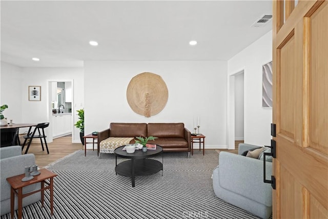 living area featuring light wood-style flooring, recessed lighting, visible vents, and baseboards