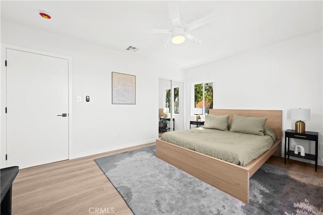 bedroom with visible vents, baseboards, wood finished floors, and a ceiling fan