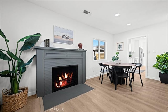 dining space featuring light wood-type flooring, visible vents, baseboards, and a fireplace