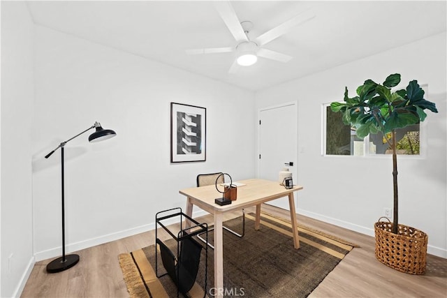 office area with baseboards, light wood-style flooring, and a ceiling fan