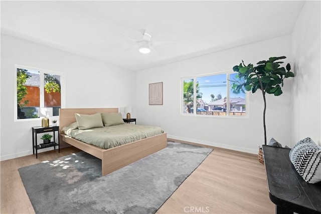 bedroom with a ceiling fan, wood finished floors, and baseboards